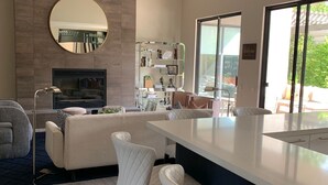 Cozinha moderna com ilha central, banquetas, forno embutido e uma grande janela com vista para o exterior.