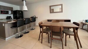 Eine moderne Küche mit Essbereich, darunter ein Holztisch und Stühle, eine Mikrowelle und ein Kühlschrank.