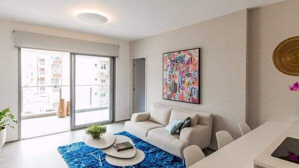 Un salon moderne avec un canapé, une table basse et un grand tableau abstrait accroché au mur.