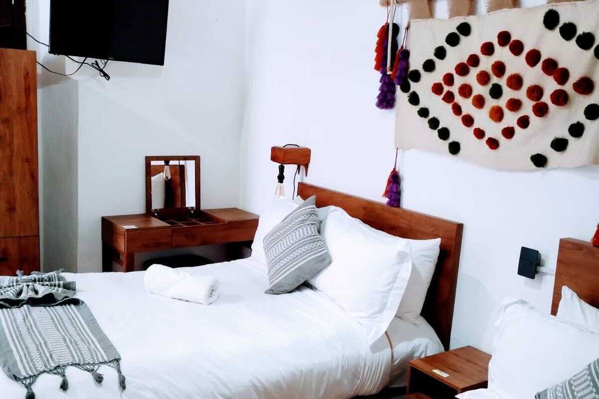 Une chambre avec deux lits, un téléviseur fixé au mur et une décoration murale.