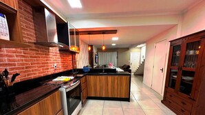 A modern kitchen with a brick backsplash, wooden cabinets, and a central island. - Duplex 02 Suites - Cond.Fechado 08 P (Gramado)