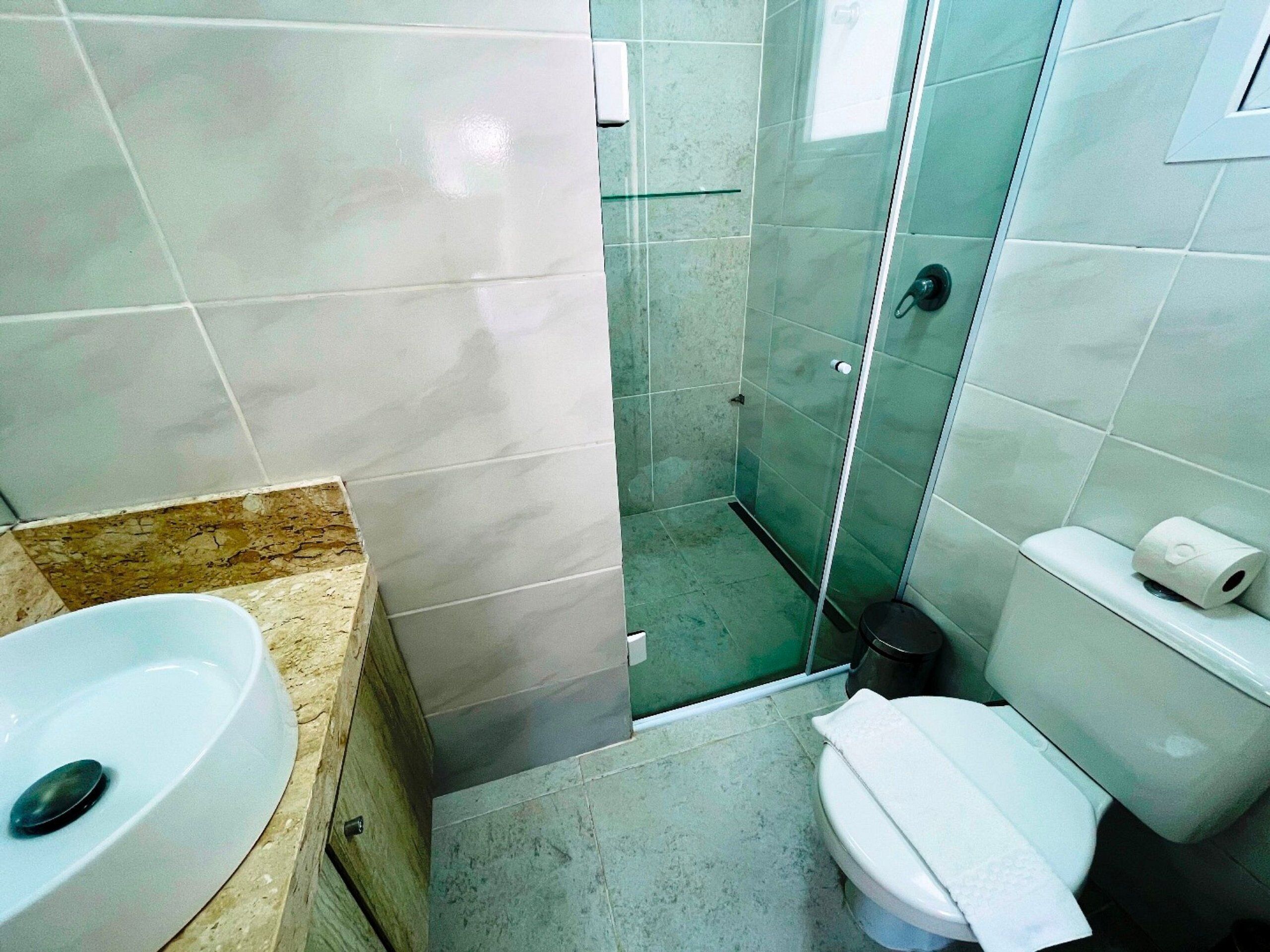 A bathroom with a sink, toilet, and glass shower enclosure.