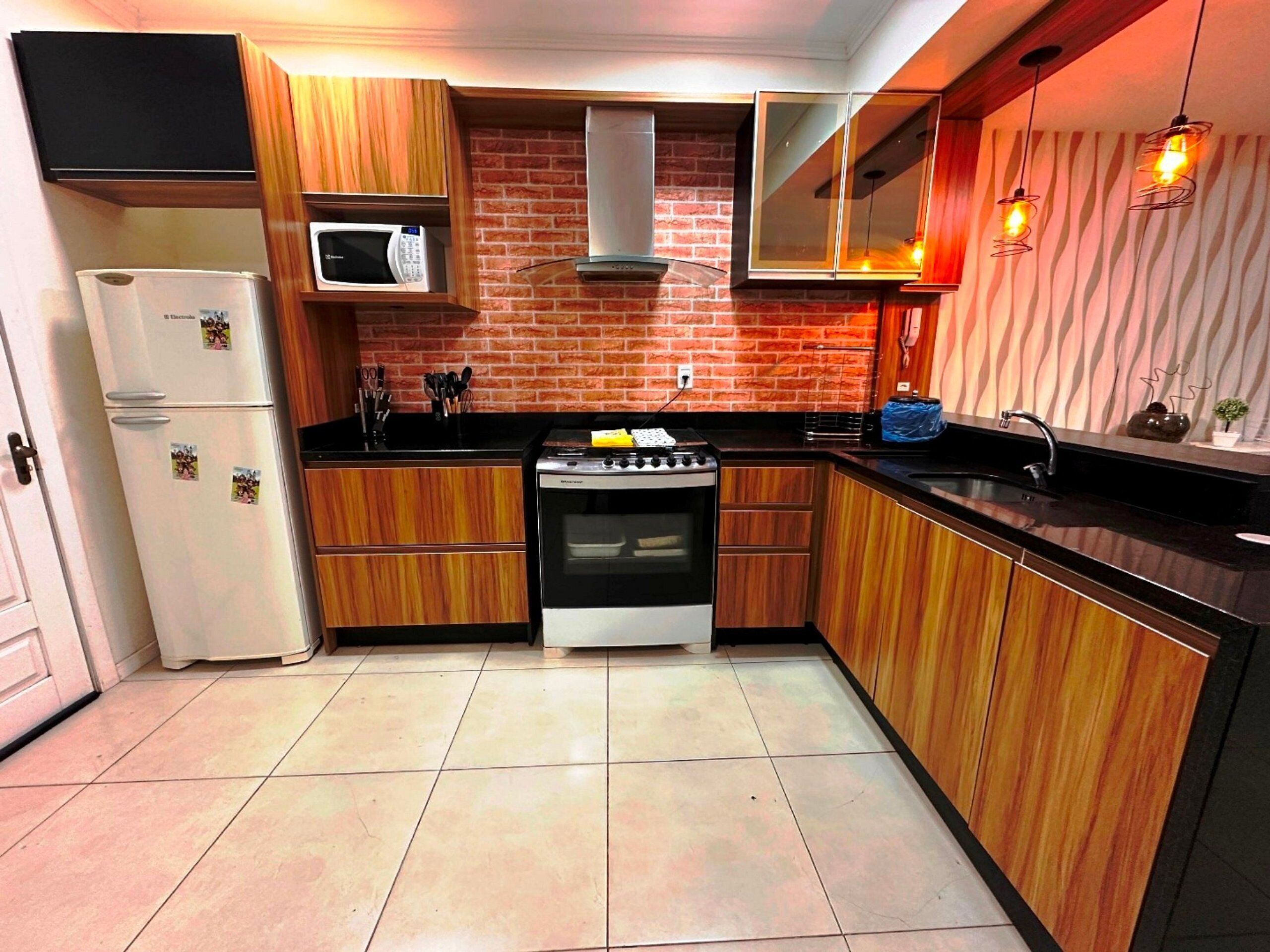 A compact kitchen with wooden cabinets, a microwave, a stove, and a sink.