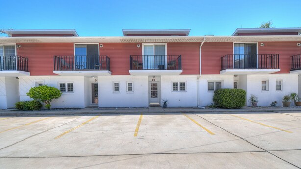 A row of red and white buildings with balconies, numbered 9 to 10, and a parking lot in front. - Cardinal Townhomes by Elliott Realty (Myrtle Beach)