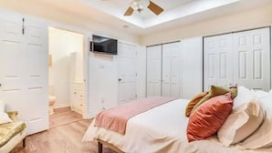 Een slaapkamer met een bed, een televisie en witte inbouwkasten.
