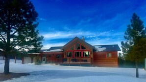A large log cabin with a prominent front porch and a covered deck area. - Three Bears Cabin (Angel Fire)
