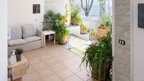 A spacious patio with a stone archway, a sofa, a small table, and various potted plants. - Villa Maristella-Positano Center-Guest 10 Adults+3 Kids-6 Bedrooms, 6 Bathrooms  (Positano)