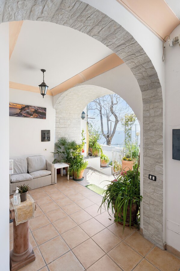 A spacious patio with a stone archway, a sofa, a small table, and various potted plants. - Villa Maristella-Positano Center-Guest 10 Adults+3 Kids-6 Bedrooms, 6 Bathrooms  (Positano)