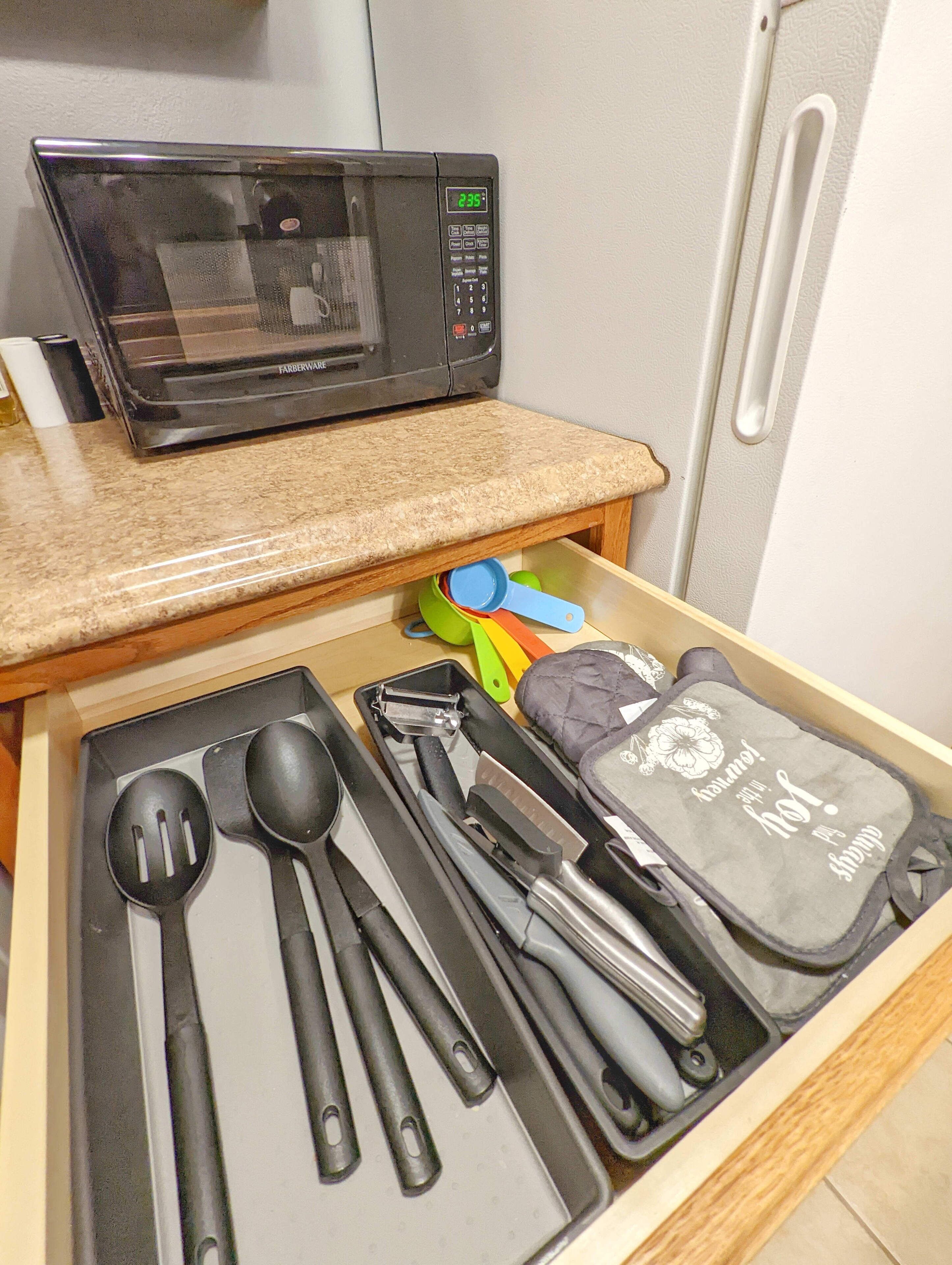 Un tiroir de cuisine contenant un four à micro-ondes, des spatules et des tasses à mesurer.