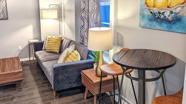 A modern living room with a sofa, a small table, and a dining table with chairs. - Tanner Bldg Apt 4 - 1 bedroom (Downtown) (Bay City)