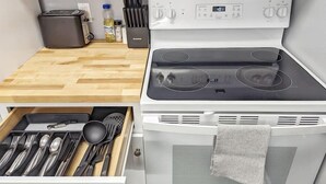 A modern kitchen with a white stove, a wooden countertop, and a drawer with utensils. - Tanner Bldg Apt 4 - 1 bedroom (Downtown) (Bay City)