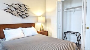 A neatly made bed with striped bedding, a bedside lamp, and a wall art piece. - Tanner Bldg Apt 4 - 1 bedroom (Downtown) (Bay City)