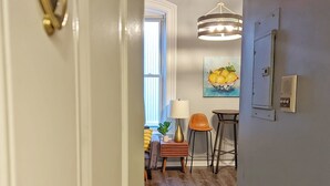 A hallway with a white door, a dining area with a table and chairs, and a painting on the wall. - Tanner Bldg Apt 4 - 1 bedroom (Downtown) (Bay City)