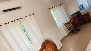 A room with a bed, two wooden chairs, a small table, and a water dispenser. - Seremei Villas (Caye Caulker)