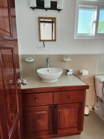 Un baño con tocador de madera, lavamanos blanco y un inodoro.