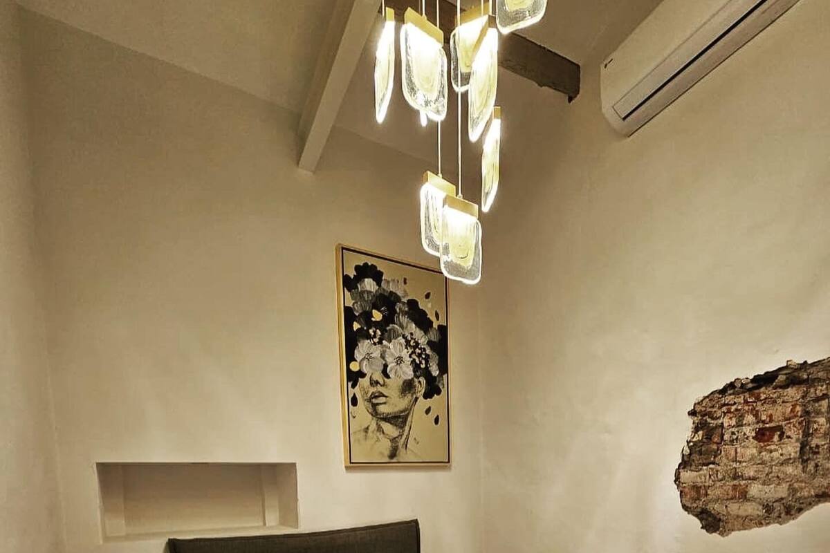 A bedroom with a bed, bedside table, and a wall-mounted artwork.