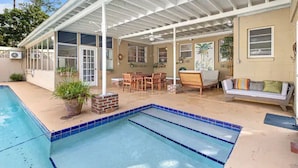 A covered outdoor area with a pool, seating, and a patio. - Hot tub, pool, bbq, game room near downtown (Ocala)