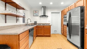 A modern kitchen with wooden cabinets, a stainless steel refrigerator, and a built-in oven. - Hot tub, pool, bbq, game room near downtown (Ocala)