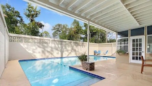 A covered outdoor swimming pool with a patio area, a white fence, and a door leading to a covered porch. - Hot tub, pool, bbq, game room near downtown (Ocala)