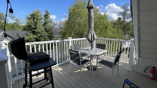 A covered outdoor deck with a grill, a table with chairs, and an umbrella. - 2b apt loft Downtown Ipswich (Ipswich)