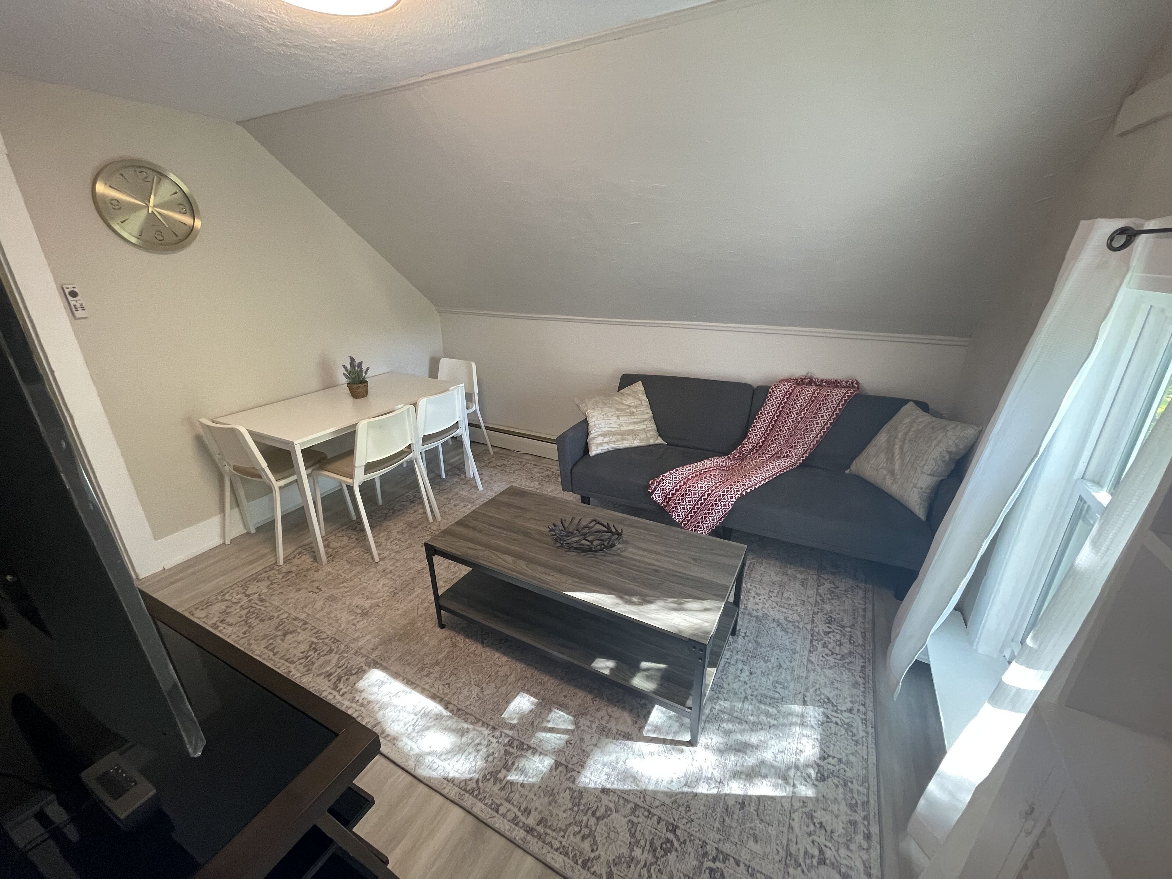 Un espacio habitable compacto con una mesa de comedor, sillas, un sofá y una mesita de centro.