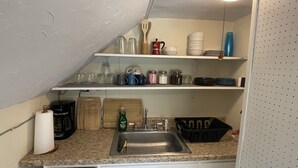 A kitchen with a granite countertop, a stainless steel sink, wooden cutting boards, and various kitchen utensils. - 2b apt loft Downtown Ipswich (Ipswich)
