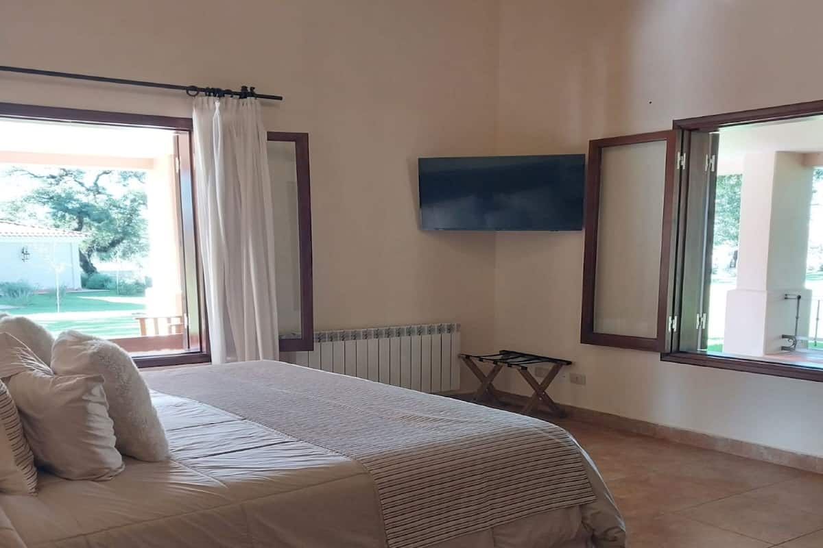 Ein Schlafzimmer mit Bett, Fernseher, Heizkörper und einem Fenster mit Vorhängen.