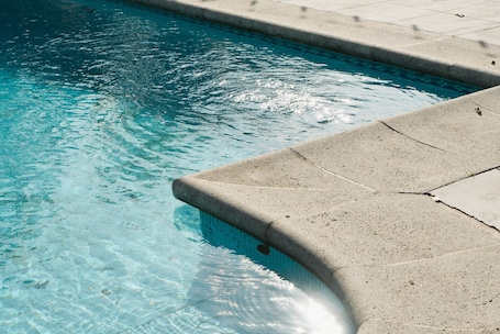 Una piscina al aire libre, sillones reclinables de piscina