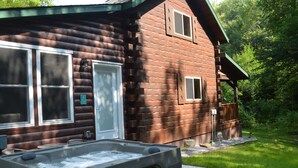 A log cabin with a hot tub in front, a door, and windows. - Cozy Secluded Cabin w/ Hot Tub, Relax, Unwind & Stargaze (Ferryville)