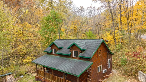 A log cabin with a green roof, surrounded by autumn foliage. - Cozy Secluded Cabin w/ Hot Tub, Relax, Unwind & Stargaze (Ferryville)