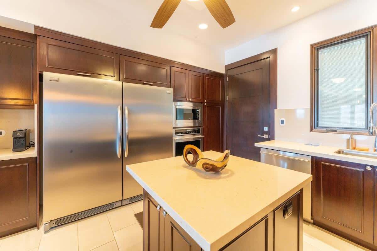 A modern kitchen with stainless steel appliances, wooden cabinets, and a central island.