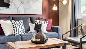 A modern living room with a grey sofa, patterned cushions, a wooden coffee table, and a vase.