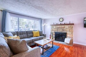Una sala de estar con chimenea de piedra, un sofá gris y una mesa de centro.