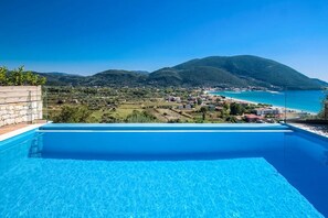 A swimming pool with a view of a coastal town and mountains. - Villa Ostria 4 Aria Drakatos (Lefkada)