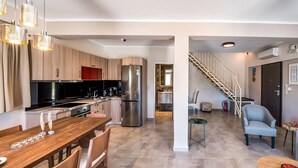 Una cucina moderna con elettrodomestici in acciaio inossidabile, un tavolo da pranzo in legno e una scala che conduce a un piano superiore.