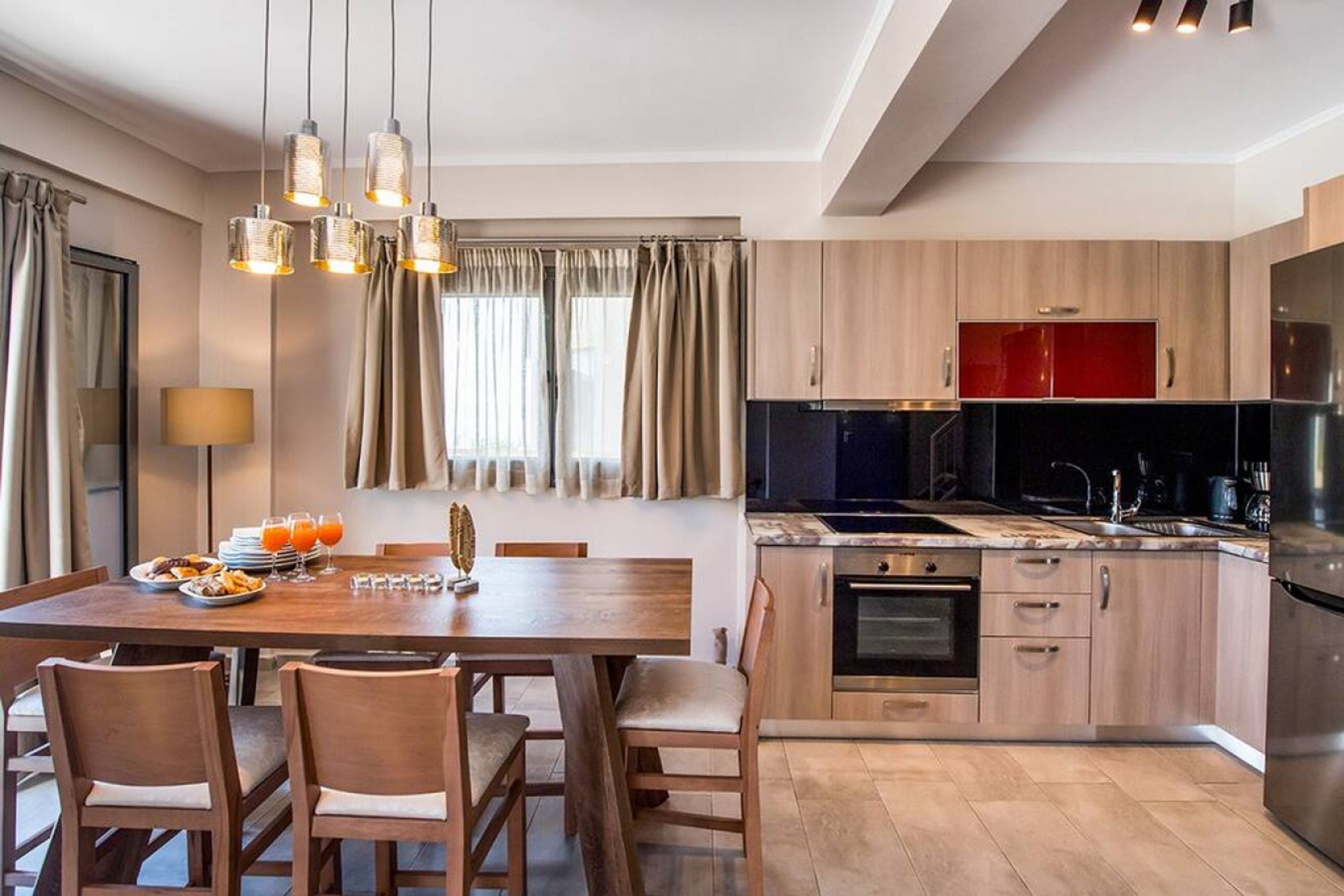 Eine moderne Küche mit Holzschränken, einem schwarzen Herd und einem Edelstahl-Kühlschrank.