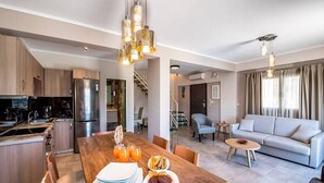 Una cucina moderna con zona pranzo, un soggiorno con divano e una scala che conduce a un altro livello.