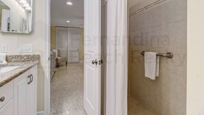 A bathroom with a shower, a sink, a mirror, and a towel rack. - 223 Lighthouse Circle 3 Bedroom Home by RedAwning (Fernandina Beach)