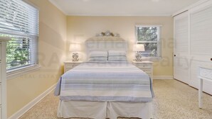 A bedroom with a bed, two bedside tables, a ceiling fan, and a window with blinds. - 223 Lighthouse Circle 3 Bedroom Home by RedAwning (Fernandina Beach)