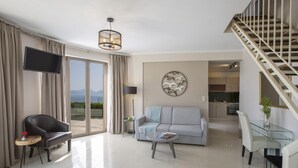 A modern living room with a sofa, armchair, and coffee table, a staircase, and a view of the outdoors. - Villa Mare 3 Aria Drakatos (Lefkada)