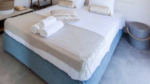 Ein Schlafzimmer mit einem großen Bett, einer Hängelampe, einer Holzleiter und einem kleinen, runden Hocker.