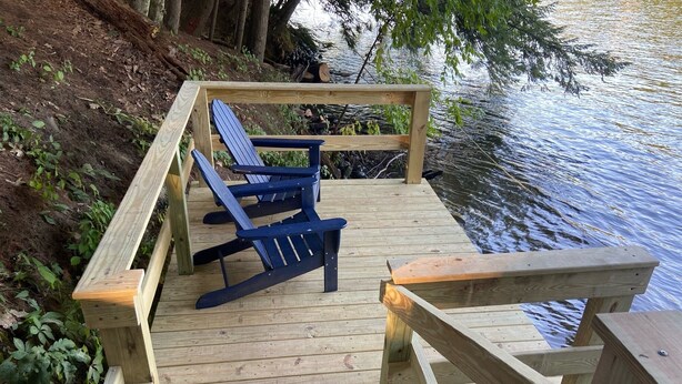 A wooden deck with a blue Adirondack chair and a wooden table. - Waterfront Pine Cabin near Saratoga, Lake George (Corinth)