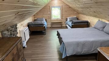 Une chambre confortable située sous les toits, avec deux lits, un mur en pierre et une fenêtre.