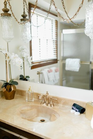 Un baño con lavamanos, espejo e iluminación de cristal colgante.