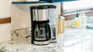 A kitchen with a coffee maker, a potted plant, and a blue cabinet.