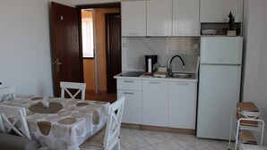 A compact kitchen with white cabinets, a sink, a coffee machine, and a refrigerator. - Charming One-Bedroom Apartment for Two (Premantura)
