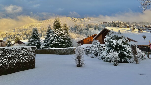 Un paysage enneigé, avec des chalets en bois et une chaîne de montagnes en arrière-plan.