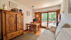 Un salon chaleureux avec un meuble en bois, un canapé et un coin repas comprenant une table et des chaises.