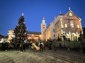 Una plaza adoquinada con un gran árbol de Navidad y un carruaje tirado por caballos.