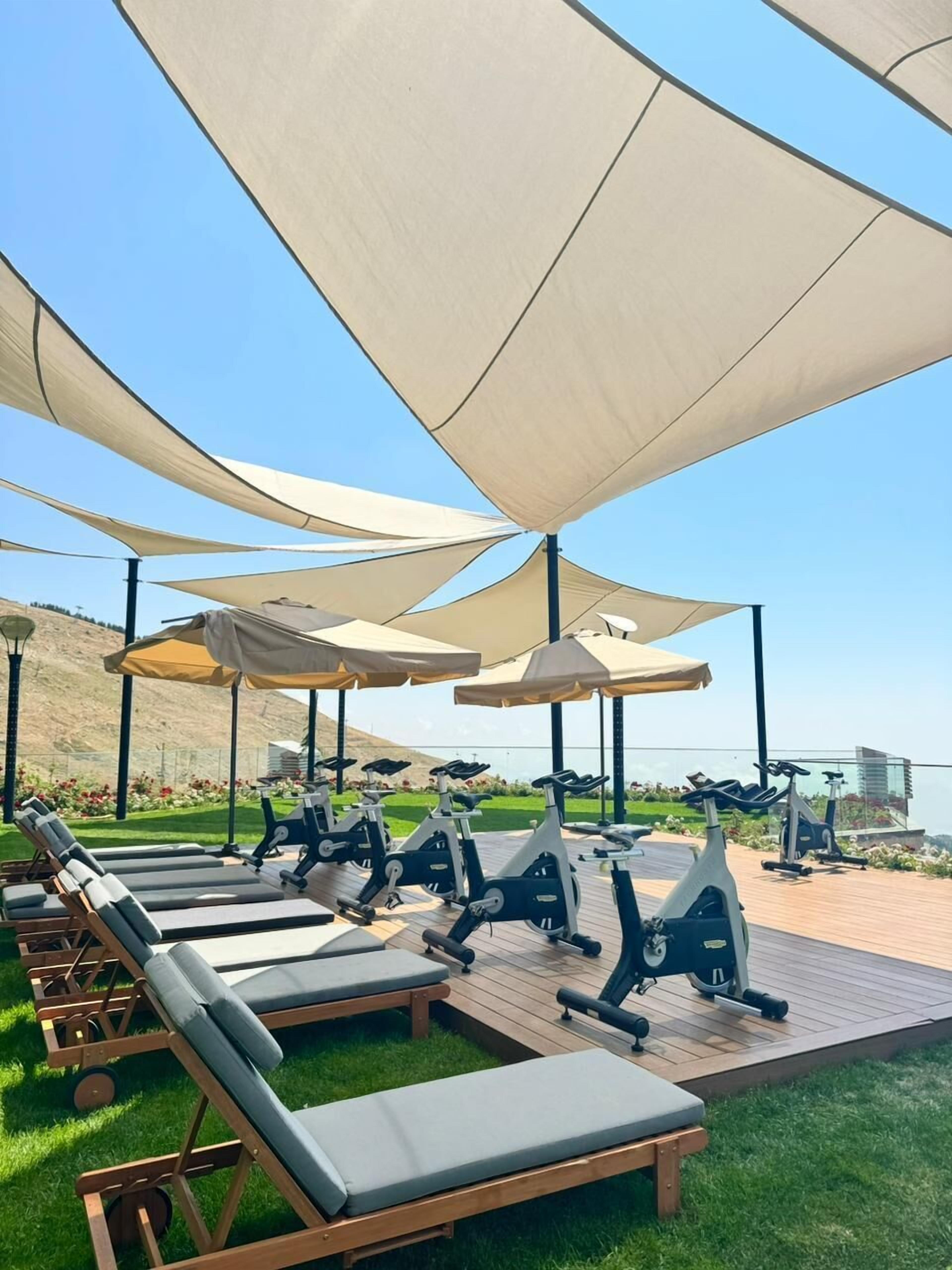 A deck with exercise bikes and lounge chairs under large canopies.
